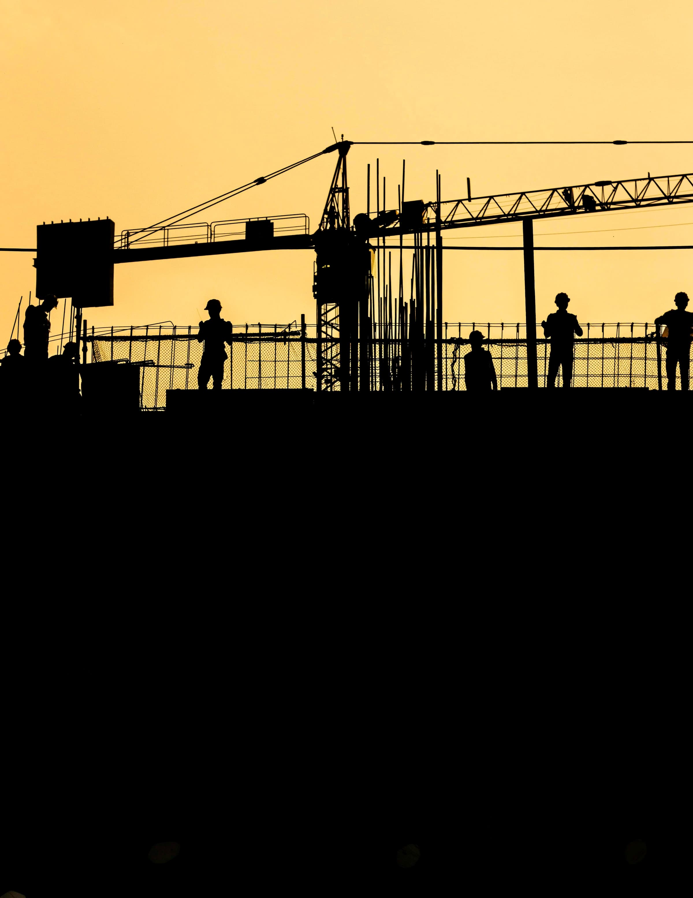 Construction workers silhouetted against the sky on an active building site