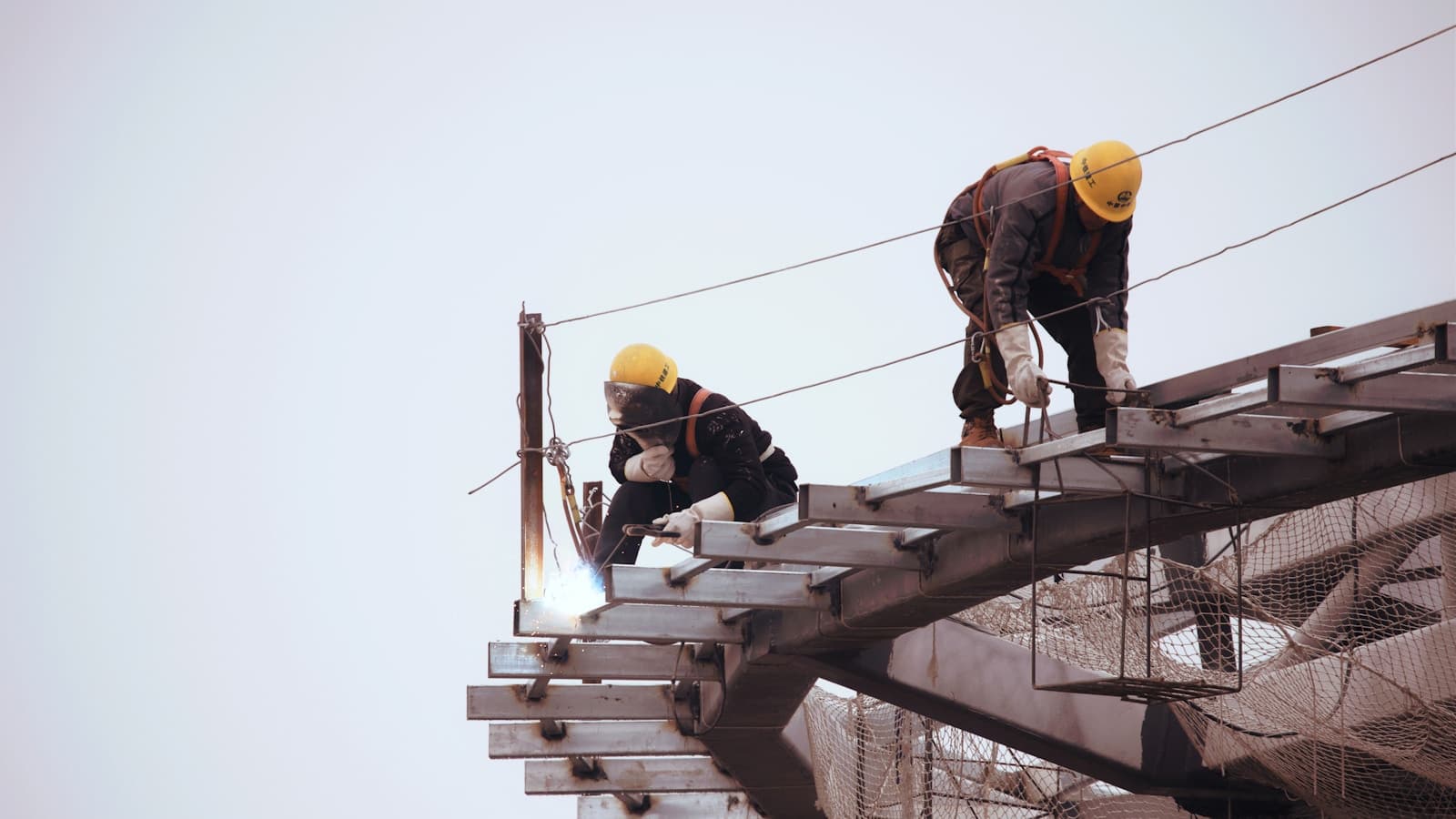 Welder working on structural steel beams at height
