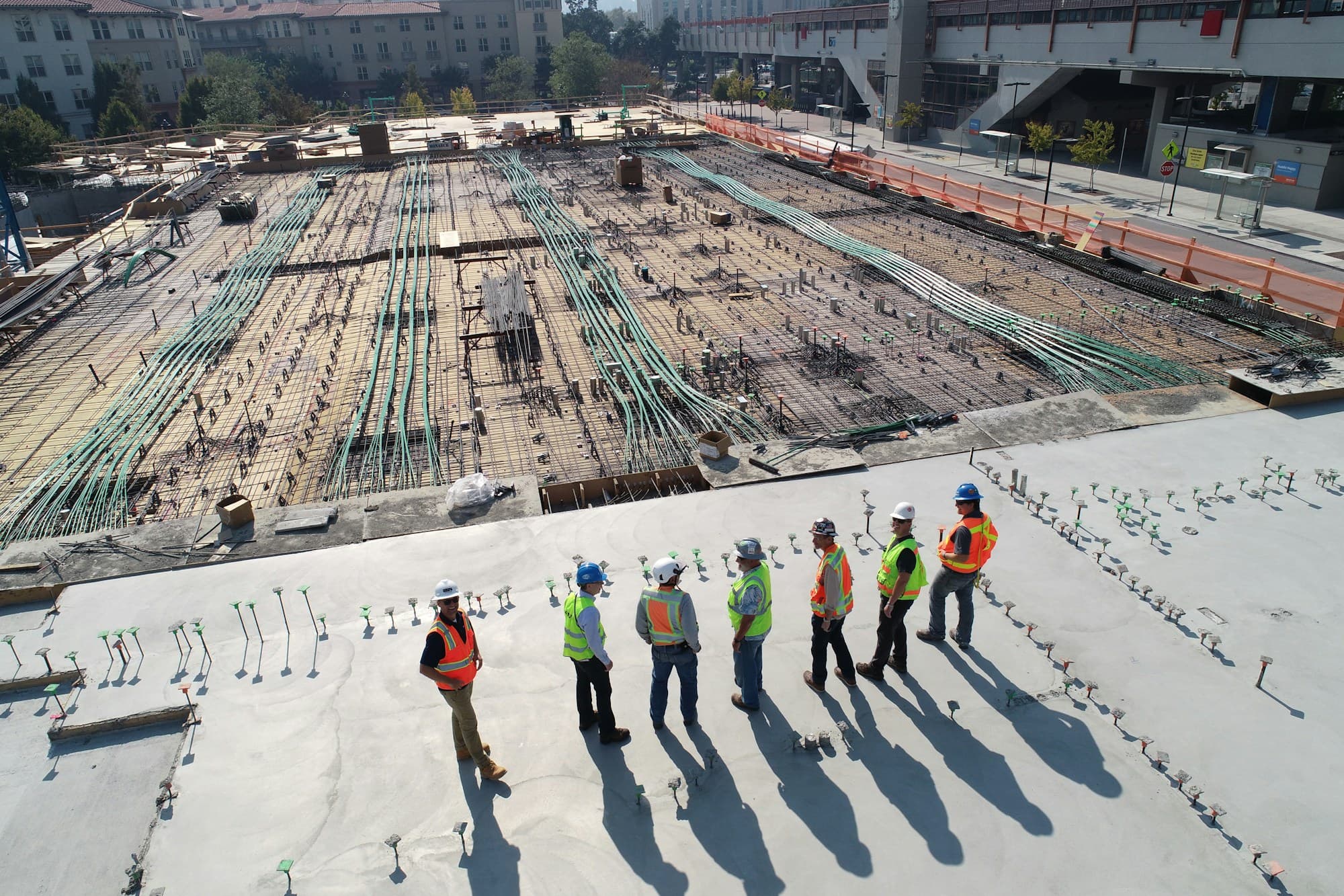A crew of construction workers standing together on an active site slab, viewed from above